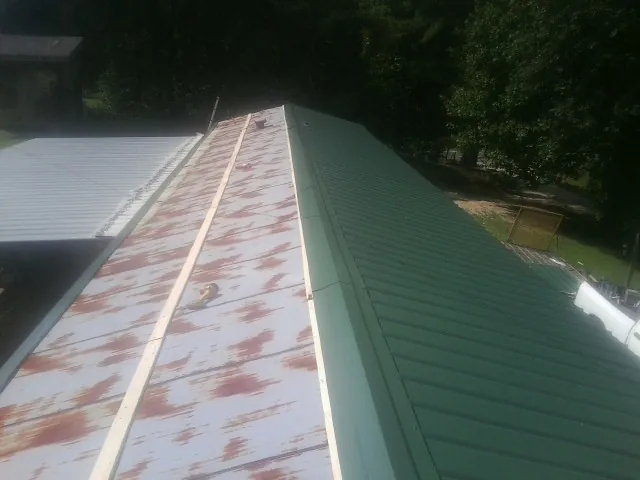 Old rusted panels beside newly installed green metal roofing — Wind Damage Roof Repair by Roofing Brothers in Jefferson