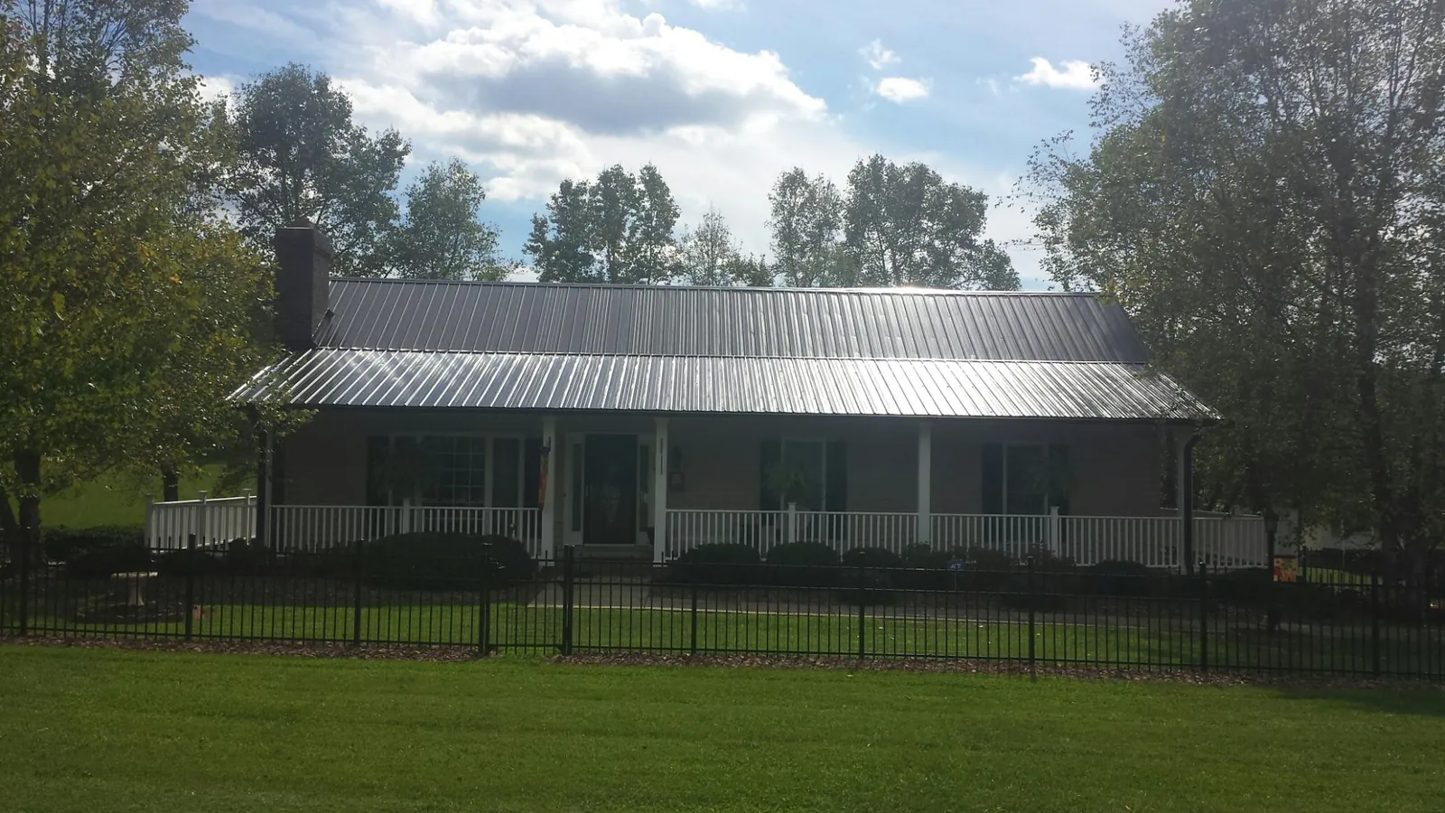 Gray metal roof on a brick ranch with a full width front porch — Gutter Guard Installation work by our crew in Jefferson